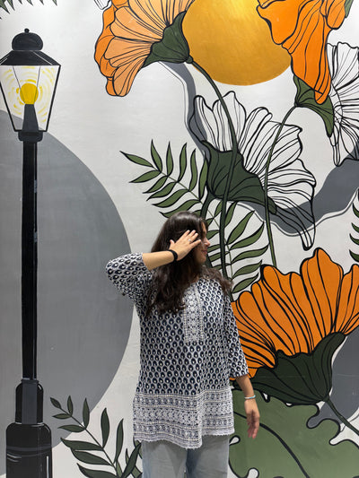 Woman standing in front of a floral mural with a street lamp on a wall.