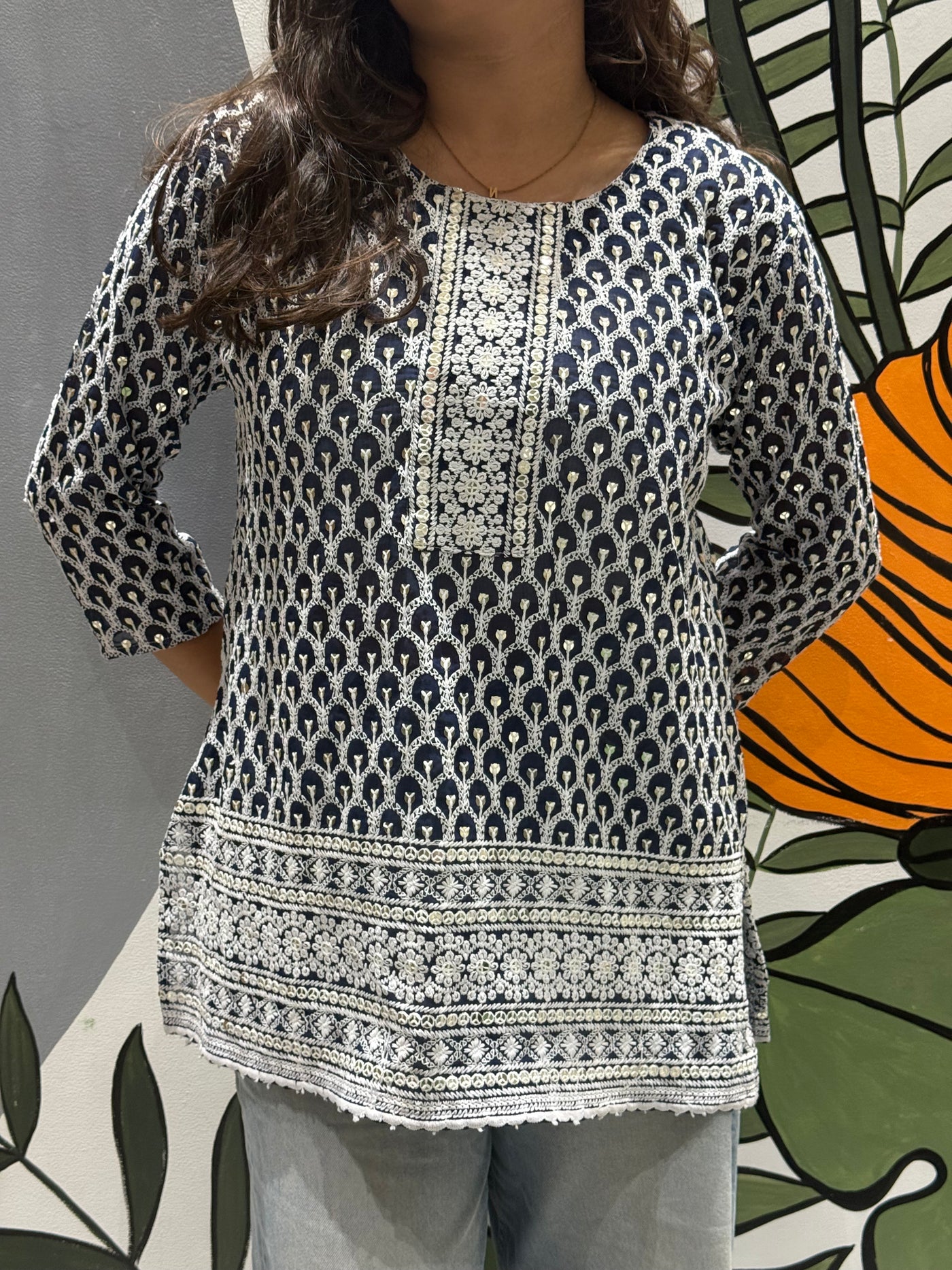 Person wearing a patterned blue and white top with a colorful background