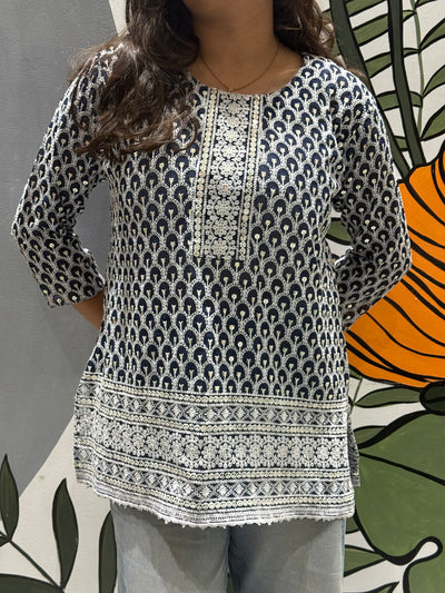 Person wearing a patterned blue and white top with a colorful background